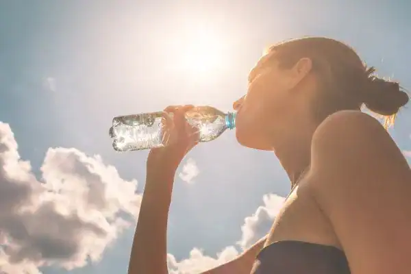 Hydration: The Secret Ingredient for a Toned Stomach and Enhanced Fitness 3 Image of woman drinking water to hydrate Shepperton Green after run.