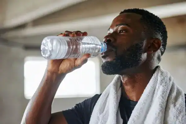 Hydration: The Secret Ingredient for a Toned Stomach and Enhanced Fitness 1 Image of man drinking water to improve hydration Shepperton Green after work out.
